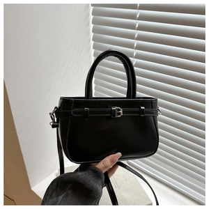 Détail du petit sac carré noir mat avec boucle argentée et doubles poignées