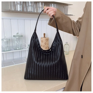 Detail of black hobo tote bag featuring fine herringbone weave texture and shoulder strap