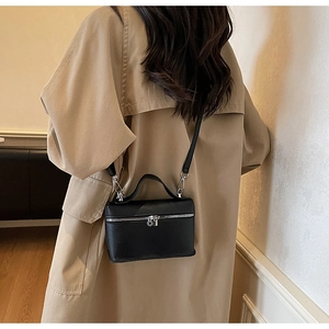 Borsa a scatola in pelle nera a grana indossata a tracolla su un cappotto cammello