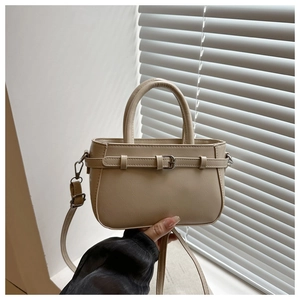 Détail du sac carré beige montrant la texture lisse et la boucle argentée décorative