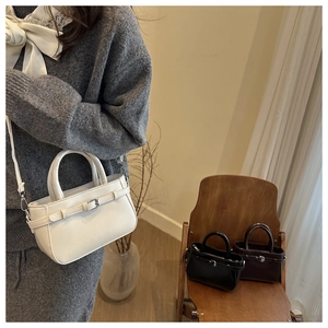 Detailed view of minimalist leather handbags in white, black, and dark brown colors