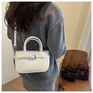 Detalle de bolso de mano en cuero PU blanco con hebilla metálica y correa ajustable