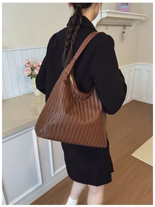 Detailed view of dark brown woven tote bag showing texture and wide shoulder strap