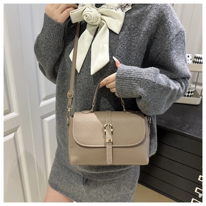 Close-up of khaki textured leather shoulder bag with metallic buckle detail on flap