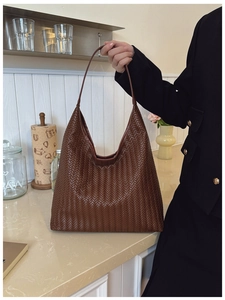 Detail of hand-woven dark brown leather texture on a large hobo tote shoulder bag