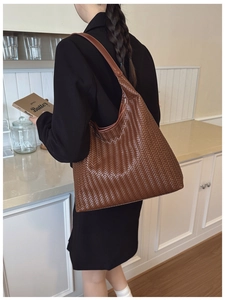Detailed view of woven brown leather tote bag with V-shaped texture and sleek shoulder strap
