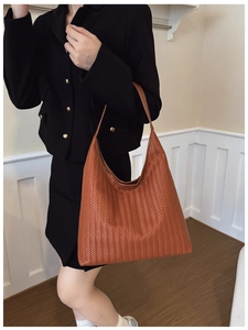 Detailed close-up of brown woven texture on a large hobo tote bag worn with a black blazer