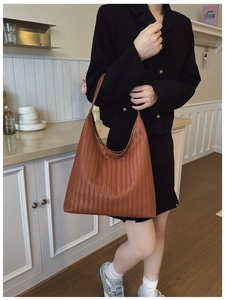 Detail shot of the brown woven leather texture on a retro oversized hobo shoulder bag