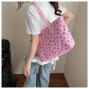 Pink shoulder tote bag with cherry print showing size and fit on a model's shoulder