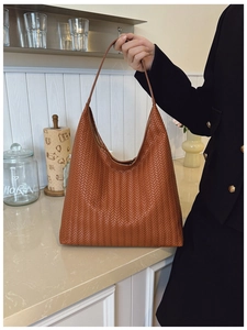 Close-up of brown woven hobo bag with leather texture and metal buckle detail