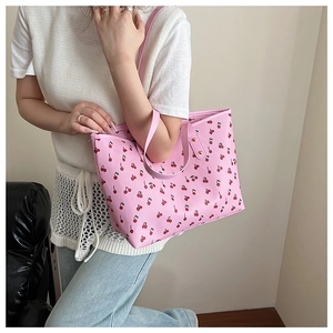 Detail of pink tote bag with cherry print and textured synthetic leather handles