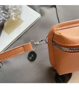 Detailed close-up of premium silver zipper and metal hook on brown lychee texture bag
