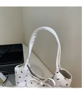 Détail du sac à main blanc à nœud papillon en tissu gaufré avec motifs de fleurs noires