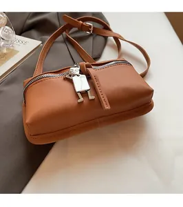 Detail of brown leather crossbody bag with silver robot charm and adjustable strap