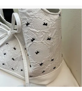 Vue détaillée du tissu blanc matelassé avec motifs nœuds noirs sur un sac cabas chic