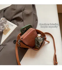 Interior view of brown crescent crossbody bag showing phone, wallet and perfume capacity