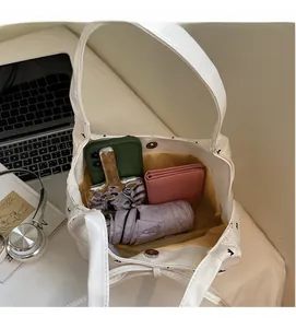 Détail du sac à nœud blanc avec imprimé de lettres montrant la grande capacité interne