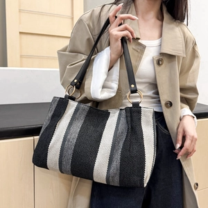 Fashionable large striped canvas tote bag with black leather straps and gold metal rings