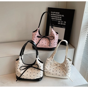 Trois sacs sous les bras avec nœuds en rose, noir et blanc avec motifs d'étoiles