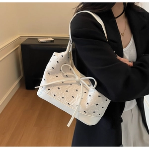 Détail du sac à bandoulière blanc plissé avec texture, motif noir et nœud décoratif