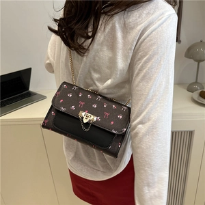 Vintage floral mini crossbody bag with gold chain strap shown on a model in home setting