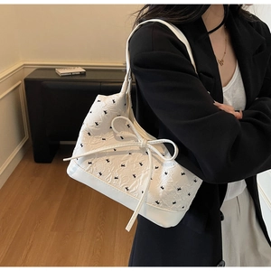 Détail du sac à bandoulière gaufré blanc avec imprimé oiseau noir et nœud fin
