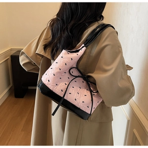 Sac bandoulière rose à motif lapin porté par un mannequin dans un intérieur chaleureux