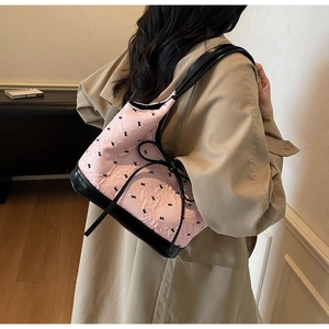 Détail du sac bandoulière rose texturé avec motifs de nœuds noirs et sangle en cuir