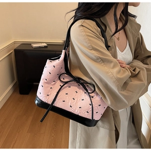 Vue détaillée du sac cabas rose avec nœud, tissu gaufré et finitions en cuir noir élégantes