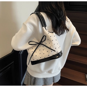 Détail du nœud et du motif lapin sur un sac sous le bras crème au style vintage chic