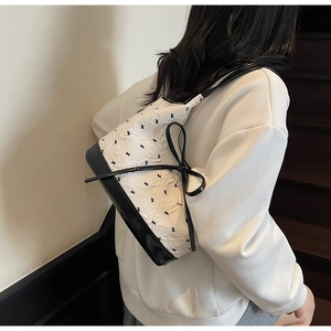 Détail d'un sac à bandoulière minimaliste avec imprimé floral et nœud noir décoratif