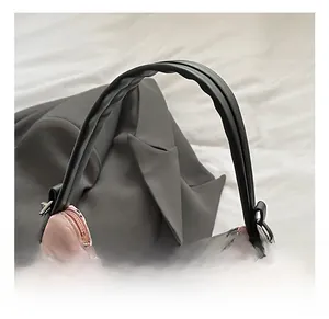 Détail du sac gaufré rose avec motifs de nœuds noirs et poignée en cuir robuste
