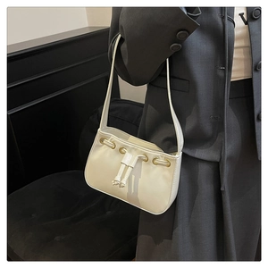 Close-up of cream shoulder bag with drawstring detail and golden eyelets on leather