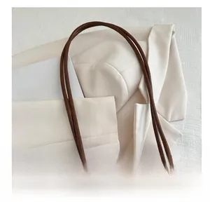 Détail du sac cabas en cuir marron avec pendentif doré et sangle tissée élégante