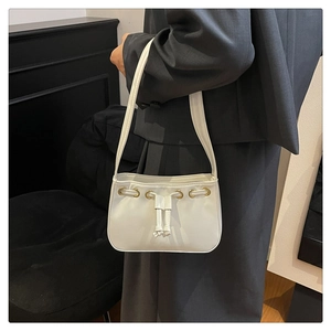 Detail of white faux leather shoulder bag with golden eyelets and bow drawstring decor