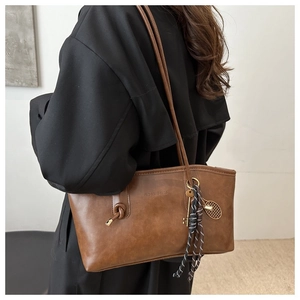 Détail du sac cabas marron vintage avec gaufrage tendance et pendentif de tennis