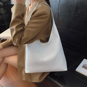 Large white woven hobo tote bag with V-shaped texture on a model in a studio setting
