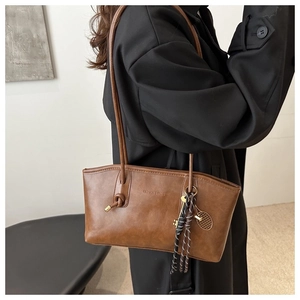 Détail d'un sac cabas vintage marron avec sangle nouée et breloque raquette de tennis