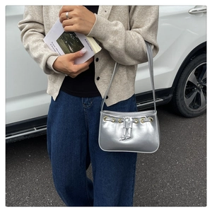 Detail of silver metallic shoulder bag showing gold grommets and drawstring texture