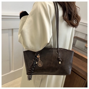 Détail du sac cabas marron foncé avec pendentif raquette de tennis et pompon rayé