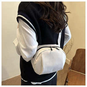 Detail of the white nylon crescent crossbody bag with black dual zippers and wide strap