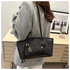 Détail du sac cabas en cuir vintage noir avec texte embossé et breloque raquette de tennis