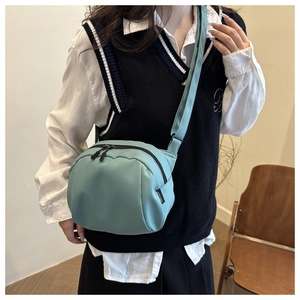 Detail of mint green nylon crossbody bag with adjustable strap and side brand label