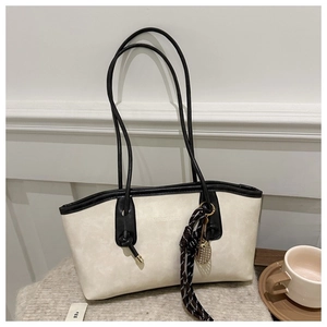 Détail du cabas blanc cassé avec bordures noires et logo gravé au style élégant
