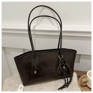 Détail du sac cabas marron vintage avec logo embossé et cordon tressé décoratif sur tissu