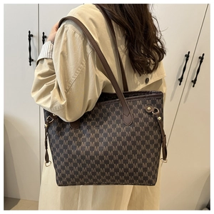 Detail of coffee brown monogram tote bag with brown leather strap and gold hardware