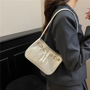 Chic cream underarm bag with drawstring and gold eyelets worn by model in minimalist setting