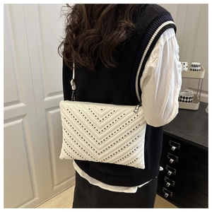 Detailed view of white envelope bag featuring V-shaped quilting and black metallic studs