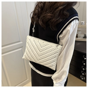 Detail view of white V-quilted faux leather shoulder bag with metallic stud embellishments