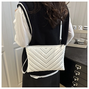 Detail of white PU leather crossbody bag with silver V-shaped rivet studs and zipper